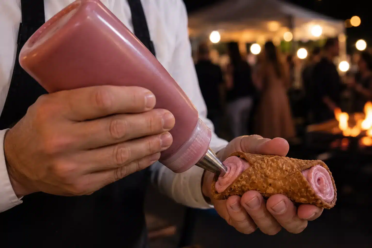 Abfüllen vor den augen der gäste eines cannoli im catering von chimigrillt